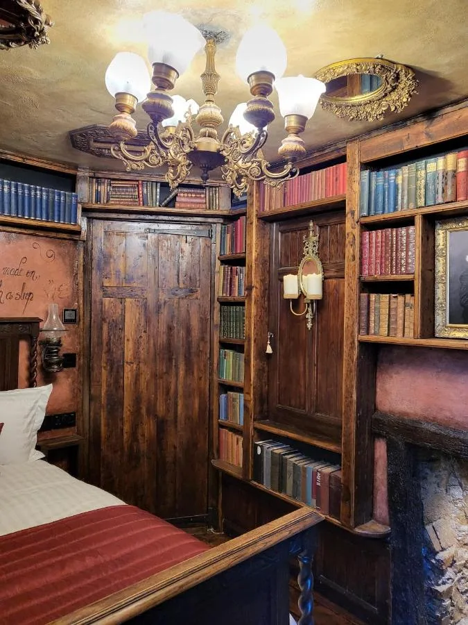 A bedroom with wooden walls, bookshelves and a bed at Hocus Pocus Tiny Hotel, York